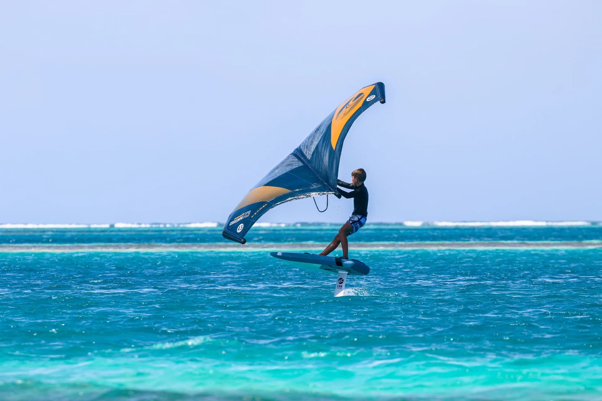 Wing-foil rider crossing turquoise water